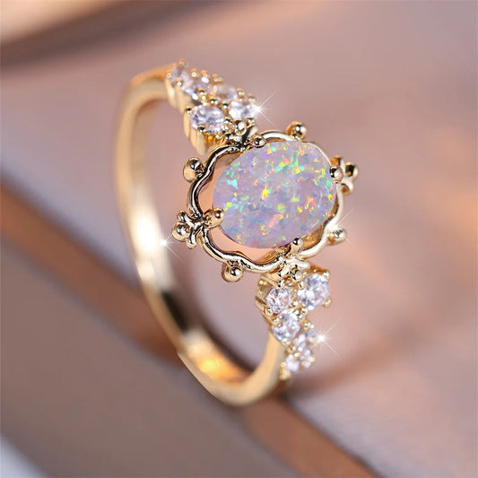 “White Fire Opal Oval Blossom Ring – Gold Filled Elegance”
A luminous White Fire Opal, glowing with shifting rainbows, rests at the heart of a delicate golden Blossom. Its oval cut catches the light with every movement,